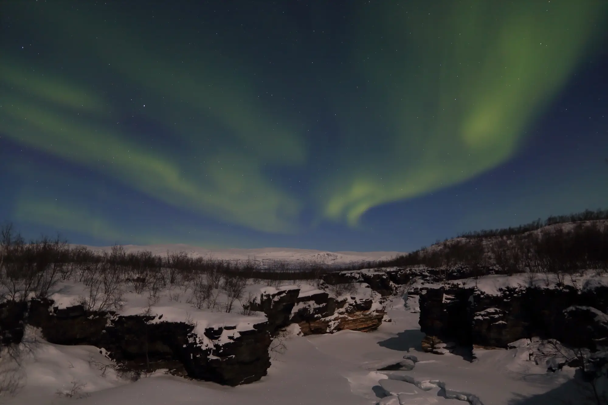 Green aurora over the frozen Abiskojåkka canyon in Abisko National Park