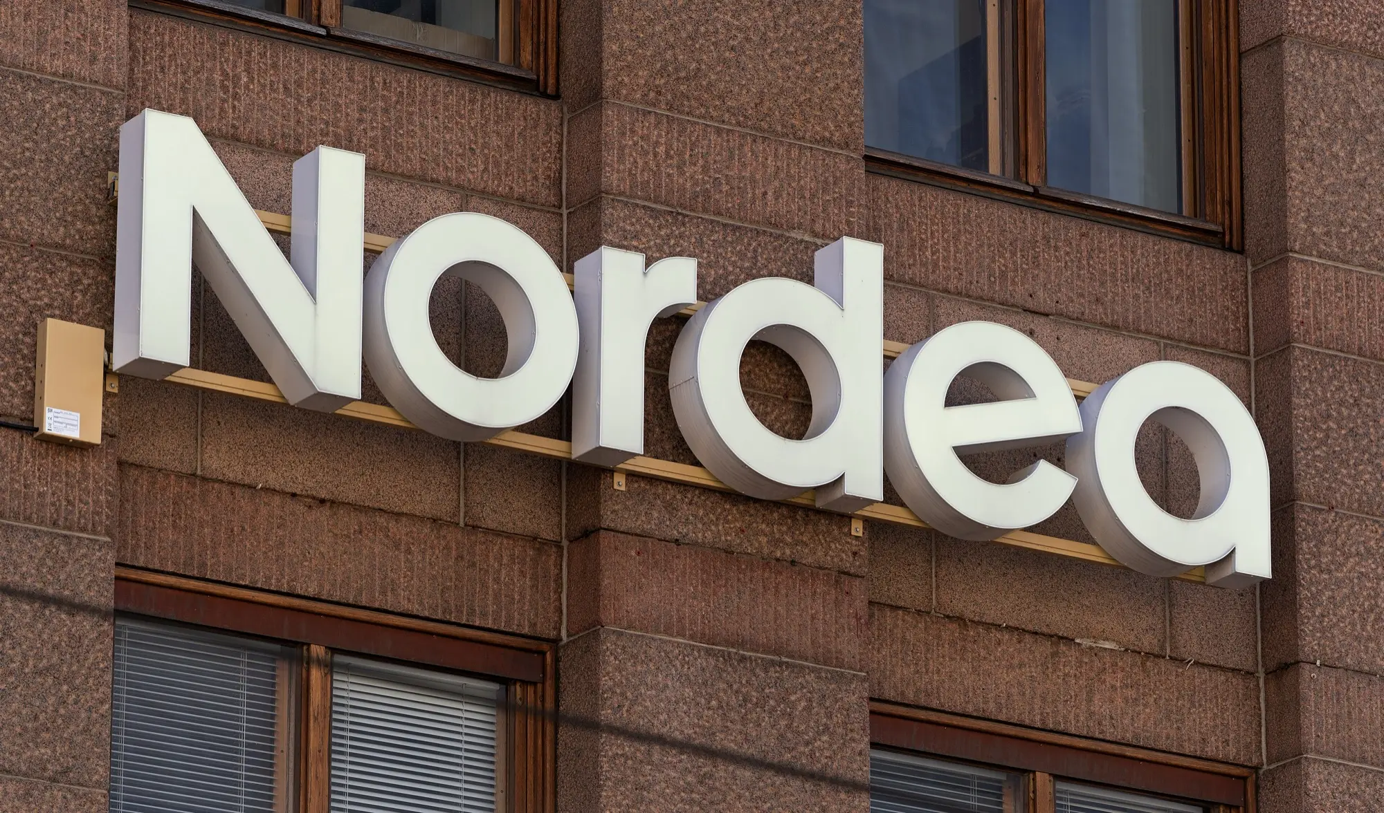 The white Nordea bank logo mounted on the red granite facade of a building in Helsinki.
