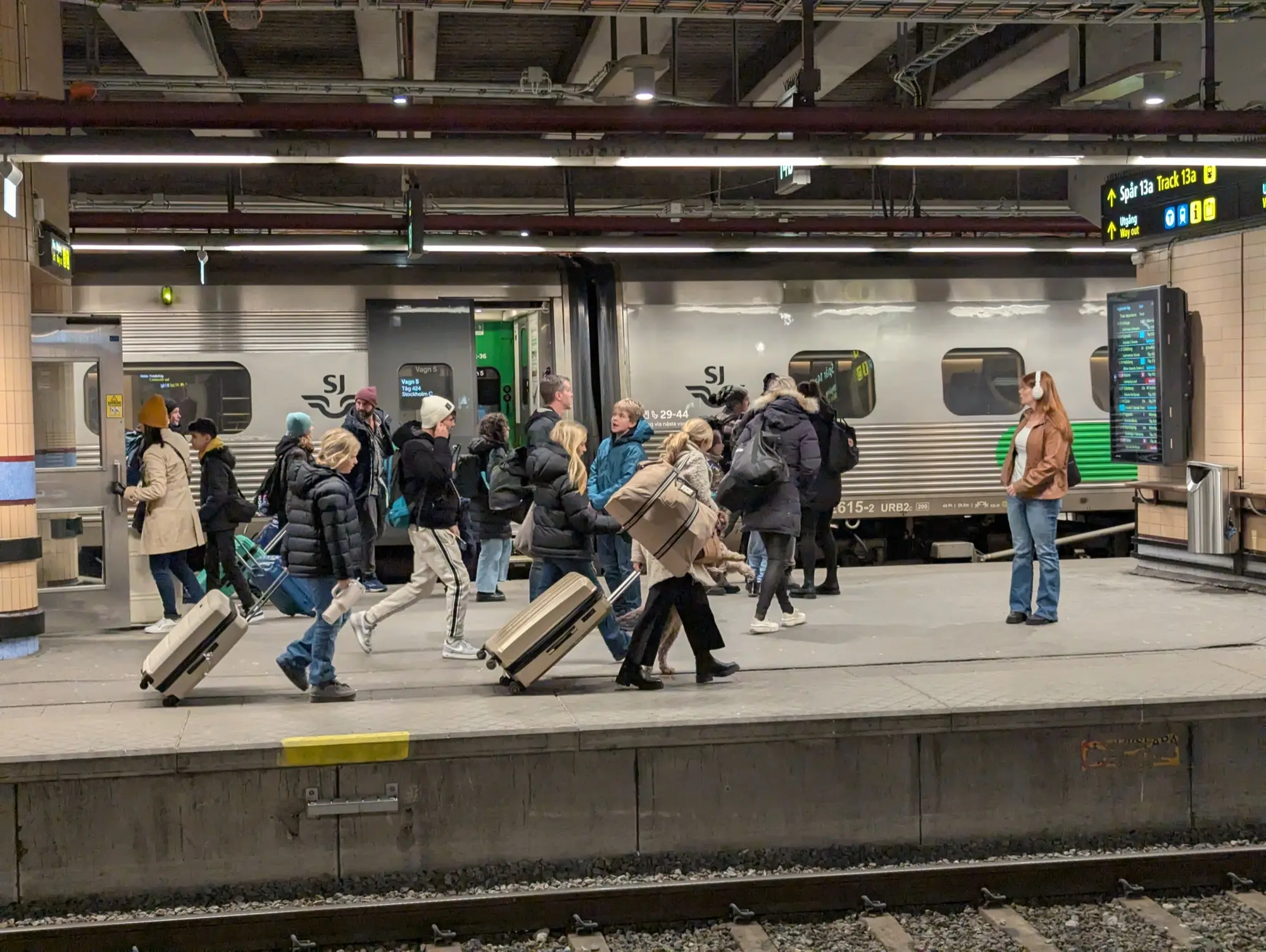 Passengers with suitcases on the platform beside an SJ X2000 train at Stockholm Central