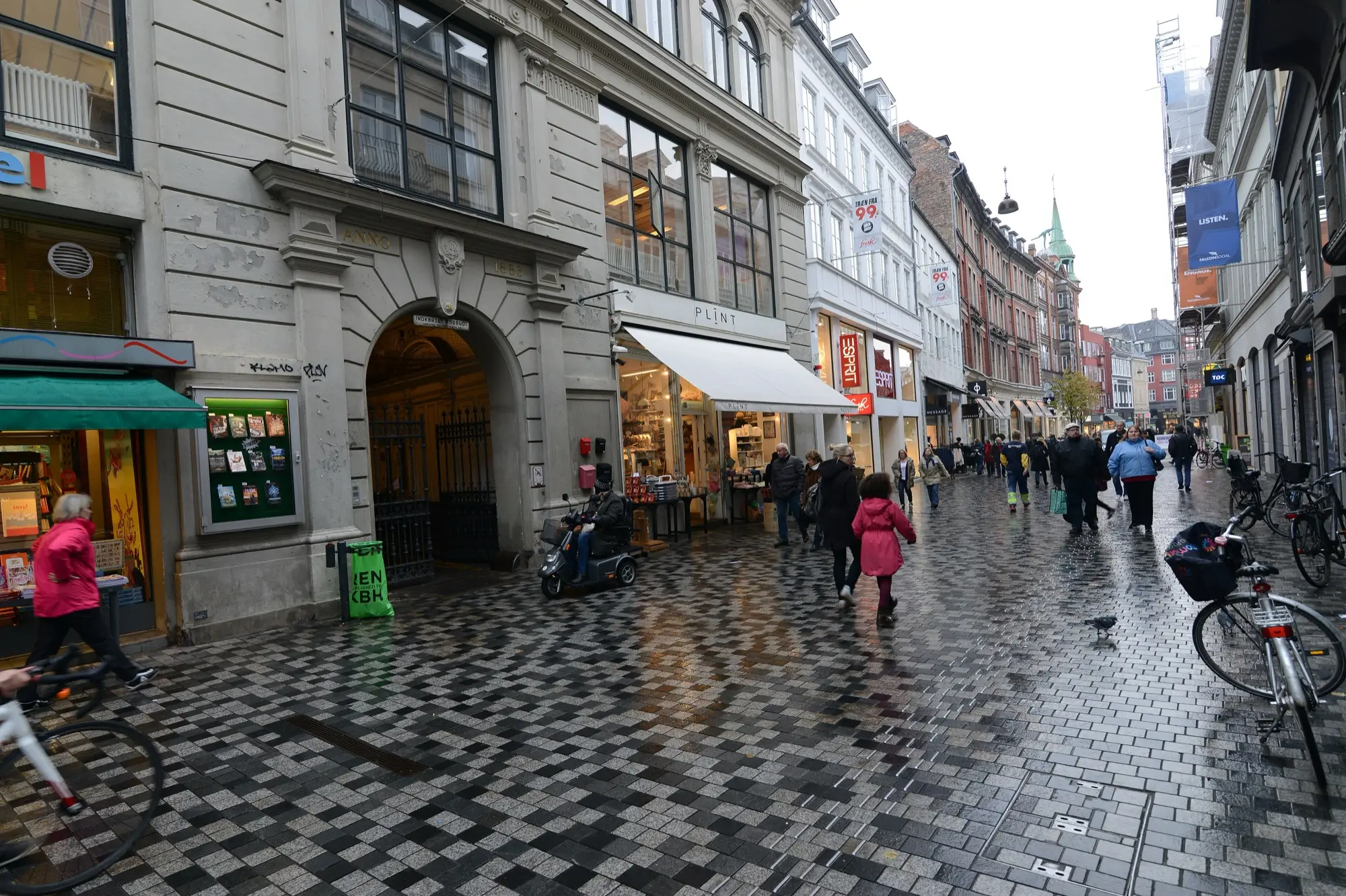 Shoppers and cyclists on Købmagergade, a pedestrian street in central Copenhagen, on a wet day