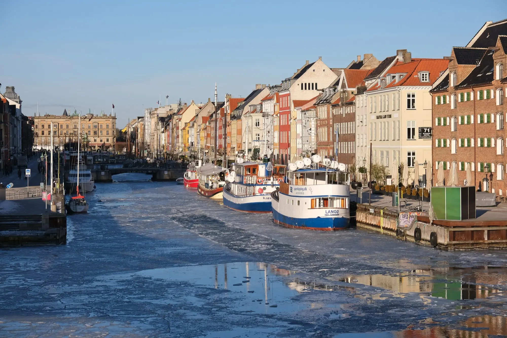 Nyhavn in Copenhagen in winter, ice on the canal and boats moored below the coloured townhouses