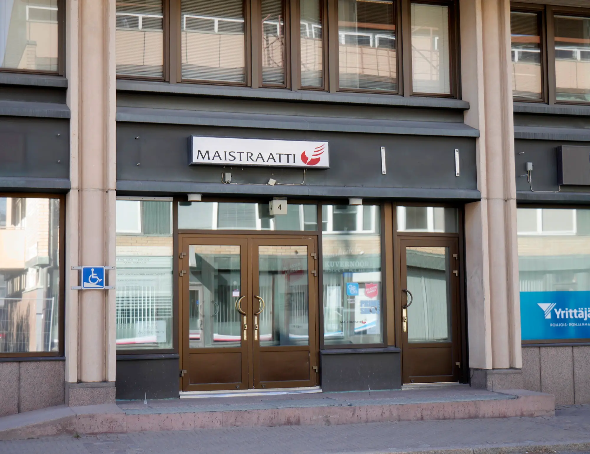 The double wooden doors of the local register office in Oulu, with a red and white Maistraatti sign above the entrance.