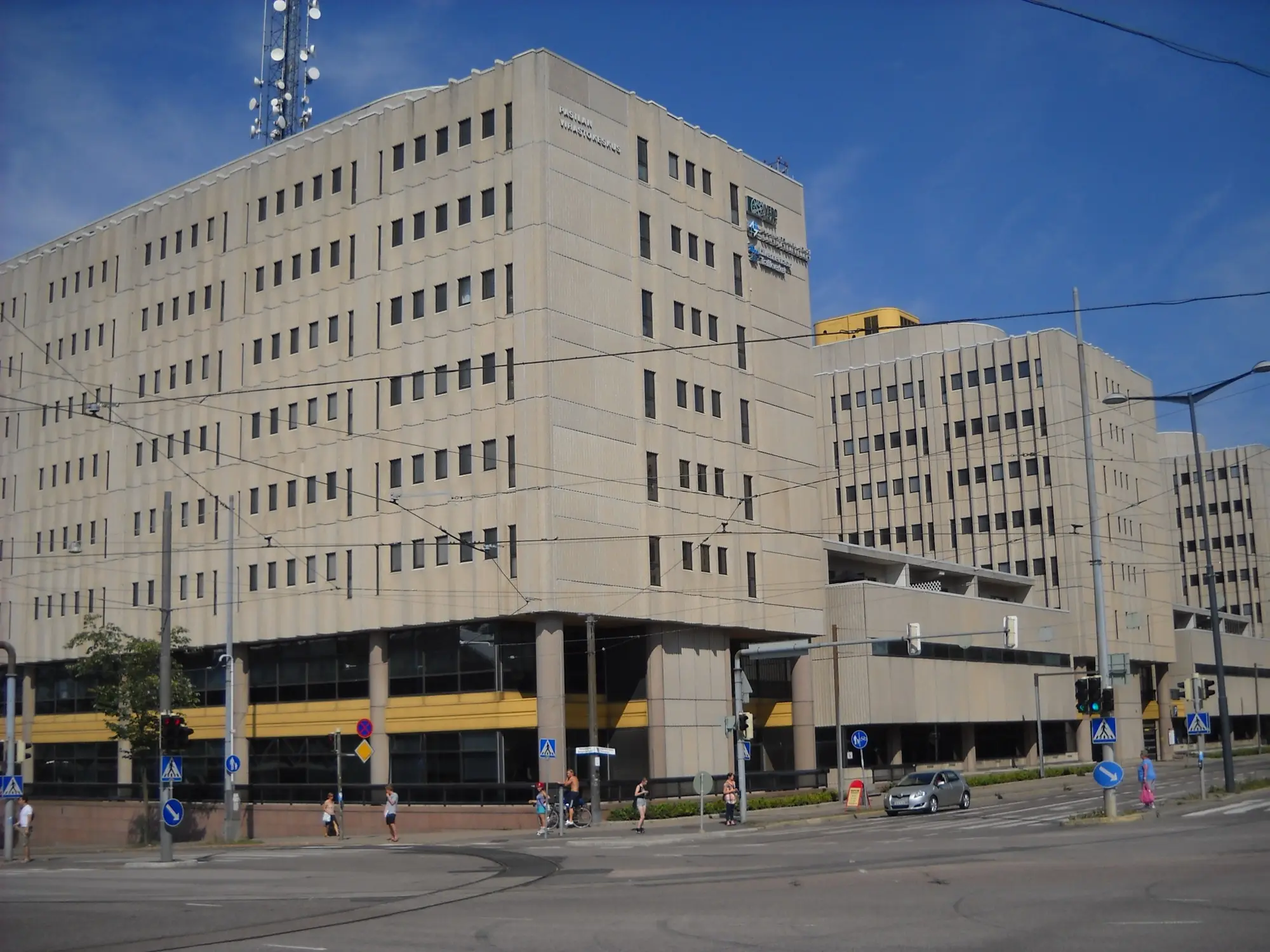 A large beige government office block in Pasila, Helsinki, with a pedestrian crossing in front on a sunny day.