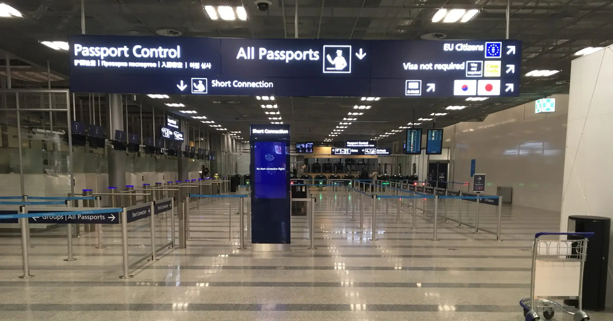 The passport control hall at Helsinki Airport, with overhead signs directing EU citizens and all passports to separate lanes.