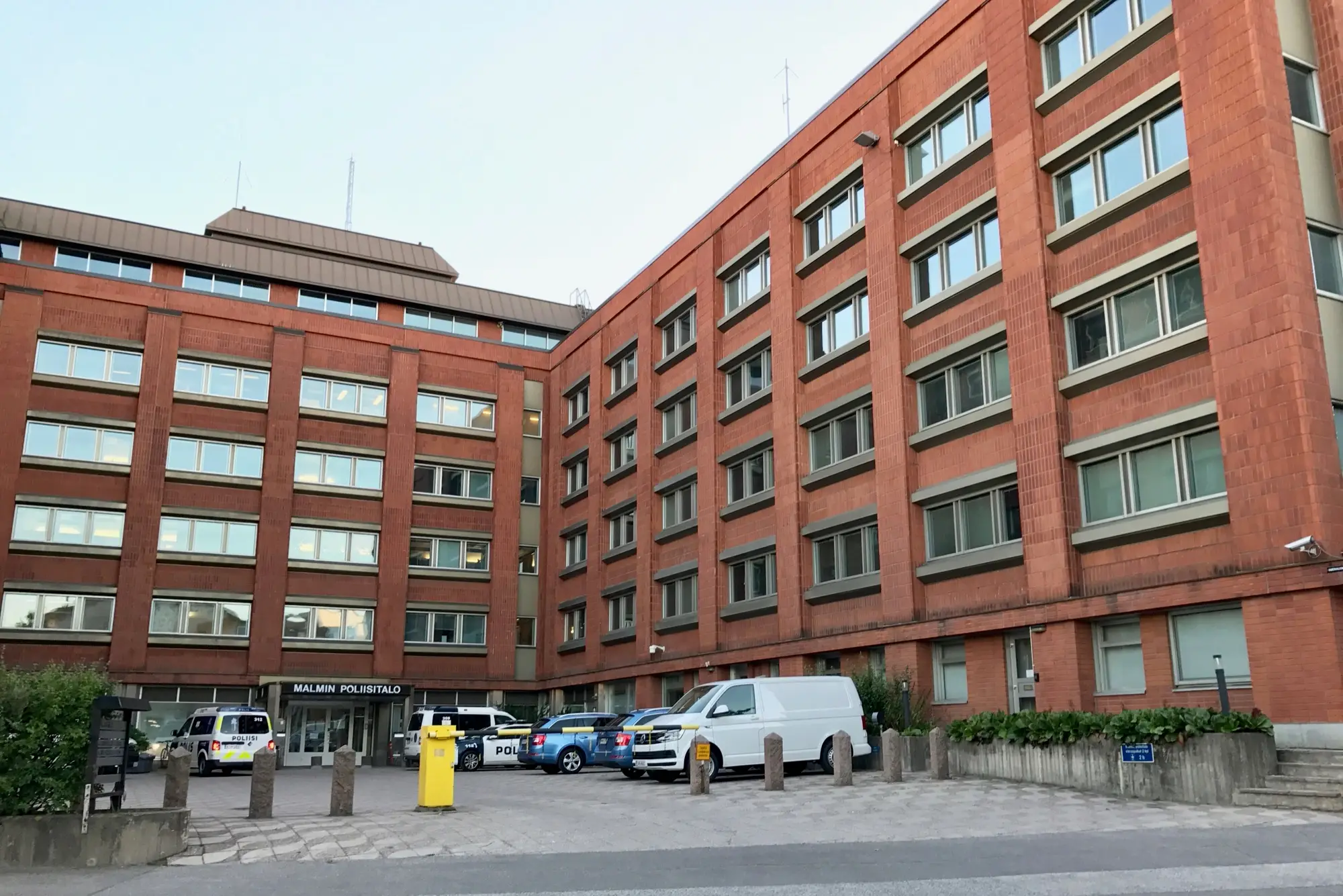 The red-brick Malmi police station in Helsinki, with police vans parked by the entrance.