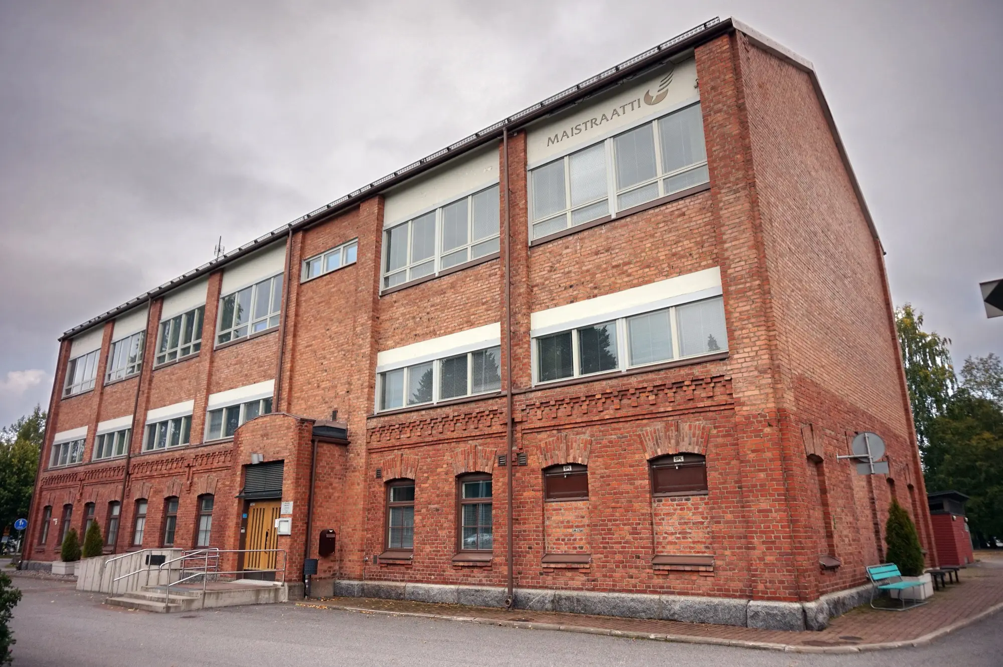 A three-storey red-brick building in Kuopio with the Maistraatti register office sign on its corner.