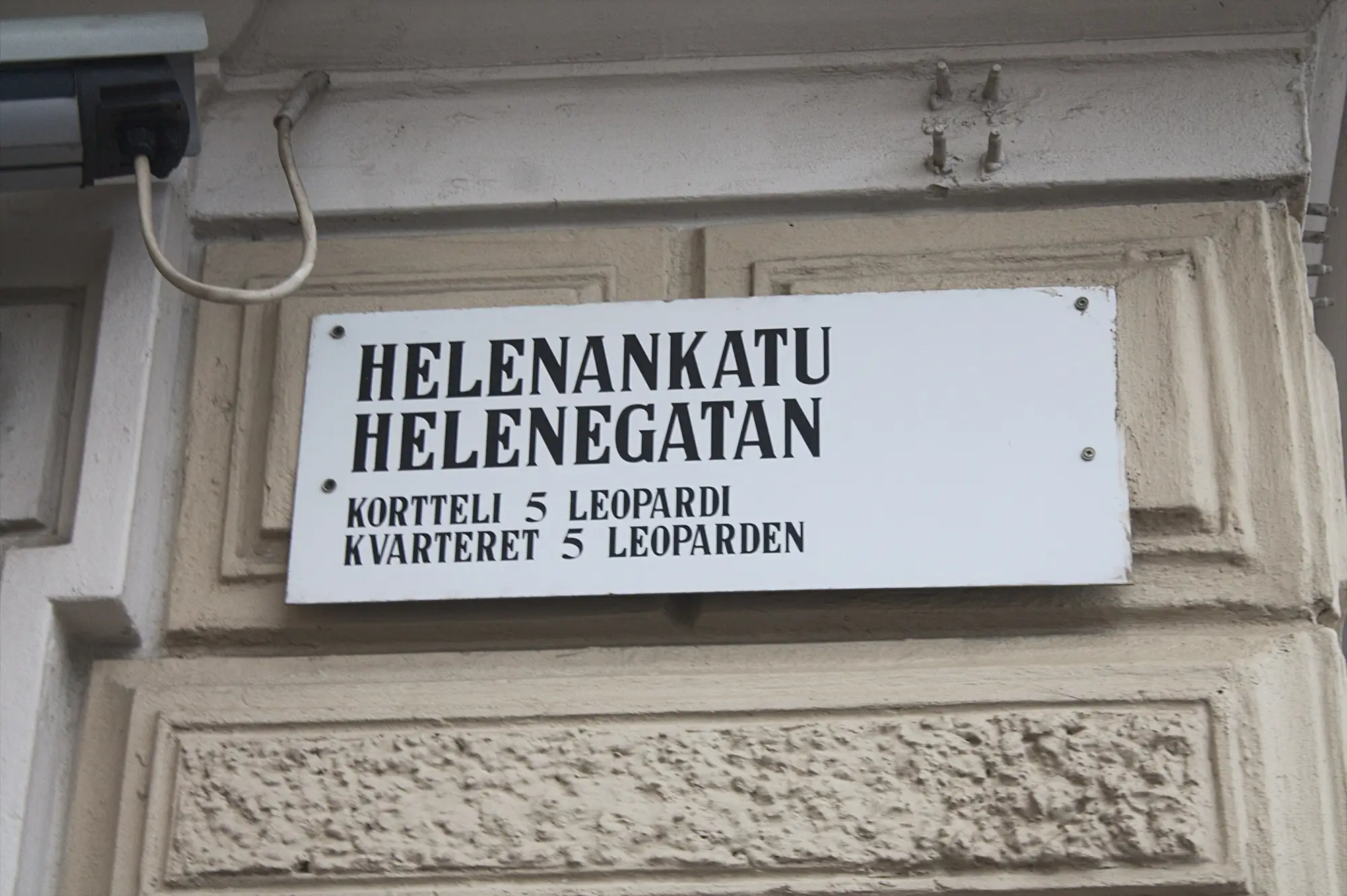 A street sign in Finnish and Swedish reading Helenankatu and Helenegatan on a Helsinki building wall.