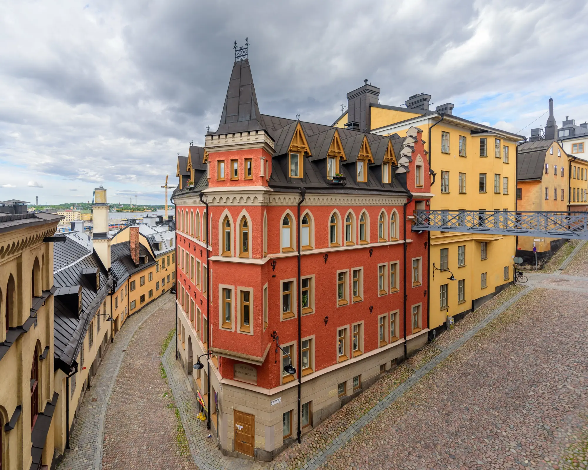 A red 1888 apartment building with a pointed turret where the cobbled streets Bellmansgatan and Pryssgränd meet on Mariaberget in Södermalm, Stockholm.