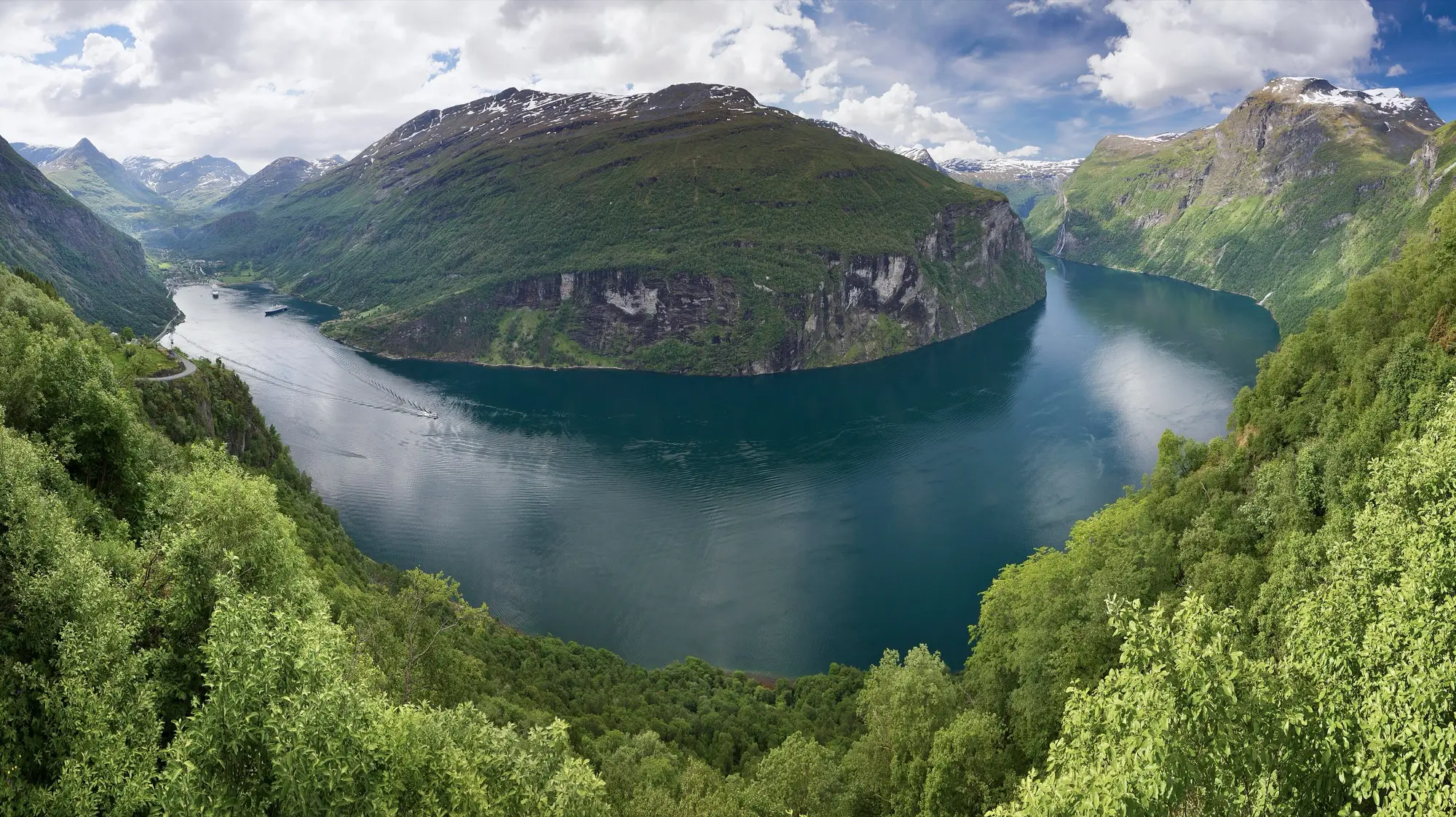 Geirangerfjord winding between steep green mountainsides, seen from the Ørnesvingen viewpoint in western Norway.