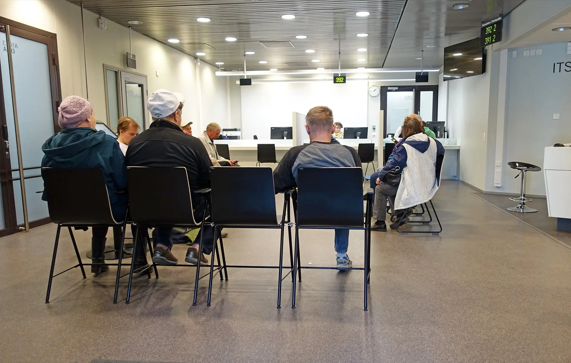 Customers wait on chairs in the bright customer service hall of the Jyväskylä tax office.